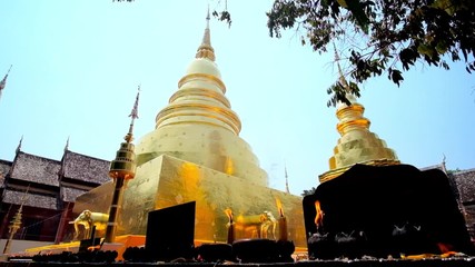 Wall Mural - CHIANG MAI, THAILAND - MAY 2, 2019: The altar with burning candles and incense sticks in front of Phra That Luang chedi (stupa) of Wat Phra Singh temple, on May 2 in Chiang Mai