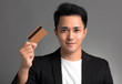 © Tom Wang - young asian business man showing credit card isolated over gray background