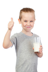 Poster - Young smiling caucasian boy with milky moustache holds glass and shows thumbs up of milk isolated on white background