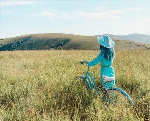 Poster - Unrecognizable romantic girl walking with bicycle in summer meadow.