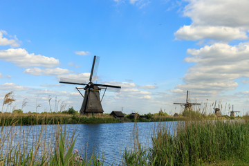 Dutch old windmills, river en blue cloudy sky on landscape, Kinderdijk in South Holland, Netherlands