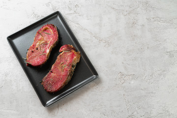 Wall Mural - Two fresh raw meat steaks on black ceramic plate