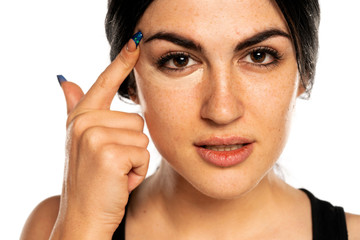 Poster - beautiful young freckled woman applying concealer with her finger