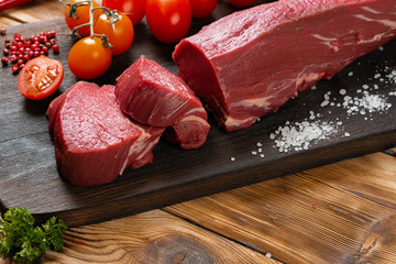 Slices raw meat fillet on wooden board