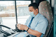young hispanic bus driver wears gloves and mask