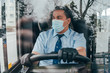 young hispanic bus driver wearing a protective mask and looks at road.