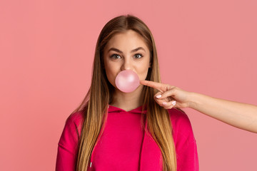 Wall Mural - Teen girl with bubble of gum. Female hand tries to burst bubble