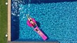 Aerial top down view of woman and child girl floating on inflatable pink flamingo and mattress in swimming pool with blue turquoise water. Summer time family vacation.
