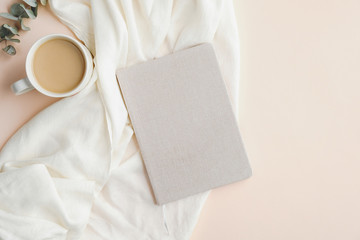 Wall Mural - Flat lay, top view home office desk table with paper notebook, blanket and cup of coffee on beige background. Modern feminine workspace concept.