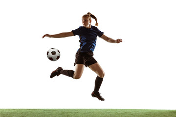 Young female soccer or football player with long hair kicking ball for the goal in flight, jumping high on white studio background. Concept of healthy lifestyle, professional sport, motion, movement.