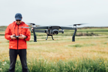 Focused image of the drone with the person handling the drone in the background. Aerial recordings. Technology concept