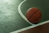 Fototapeta Sport - old orange basketball ball on green stadium floor with white curve sport background