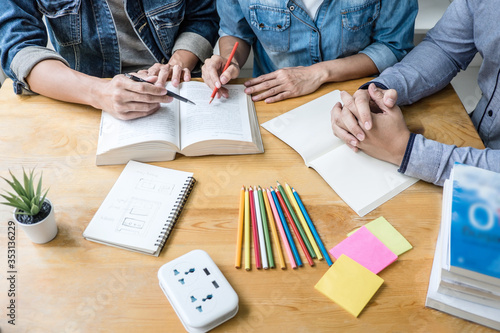 Fotomural High school tutor or college student group sitting at desk in library studying a