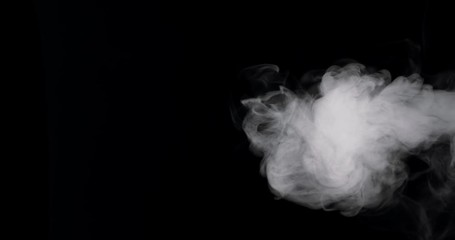 Wall Mural - plume of thick smoke flowing in against a black background.