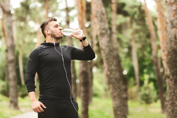 Sportsman drinking mineral water, standing in the forest