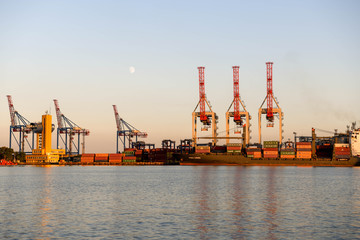 Canvas Print - The cranes in the port of Odessa at sunset with the moon in the background.