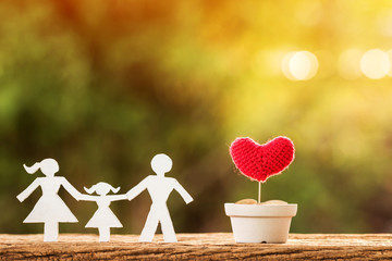 Wall Mural - A family with model and gold coins in flowerpot with grow up to red heart for love put on the wooden in the public park, saving for planned investment in the future concept.