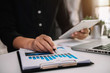 © NINENII - Business documents on office desk with laptop and smart phone and graph business diagram and man working at office.