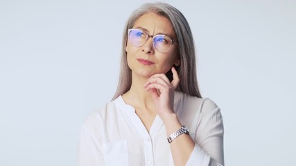 Wall Mural - A pretty nice old mature woman with long gray hair wearing glasses is coming up with good idea standing isolated over white background in studio