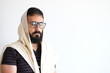 Bearded Jewish with a  Tallit (talis) . The man is standing in front of a white background and he is in the middle of a pray with he's eyes close and concentrate.
