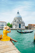 © phpetrunina14 - woman in yellow sundress sitting on pier with view of grand canal
