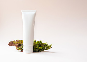 Mockup white plastic tube with facial or hand moisturizer cream or facial cleanser on tree bark on beige background with copy space. Concept bio organic beauty products with natural extract