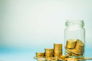 Gold coin vertically aligned in the growth direction and money in a glass jar, saving money on future spending concept.