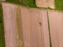 Aerial View Of Tractor Pulling Plow, Throwing Dust In Air. Combine Harvester At Wheat Field. Heavy Machinery During Cultivation, Working On Fields In Marinhas, Esposende, Portugal.
