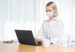 © Streetstylephoto - A young girl works with a laptop at home or in the office. antiviral mask.