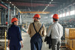 © pressmaster - Rear view of industrial engineers in hardhats walking over factory shop while discussing products