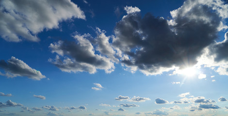 Bright beautiful blue sky with soft clouds, bright sun in the evening