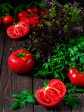 Fototapeta Kuchnia - Slice of tomato and ripe red tomatoes close-up on a dark rustic background. Ripe vegetables from the market, ingredients for the preparation of salads or dishes.