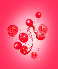 Whole and sliced cranberries with splashes of juice on a red background