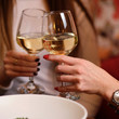 © marychka - female friends - hands clinking white wine glasses, restaurant or bar on background, close up view. evening, celebration and holidays concept