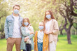 © travnikovstudio - Adorable family in blooming cherry garden in masks