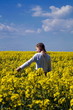 © Сергей Горельчик - A girl walks along the rape field, in the summer, stands with her back to us. touches plant flowers with hand