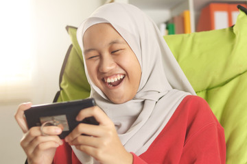 Asian Muslim Teenage Girl Plays Online Games on Phone