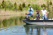© Sarah Rypma - Teenage girl on a boat reeling in a bass fish with her grandpa and dad