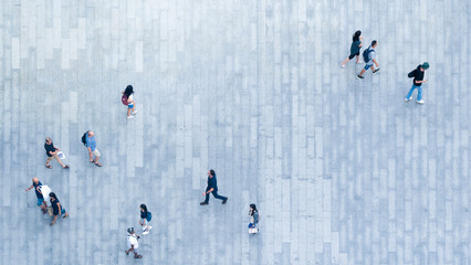 Human life in Social distance. Top view of blur people are walking in public space on concrete pavement landscape. Concept in aerial view of man and woman family with empty space.