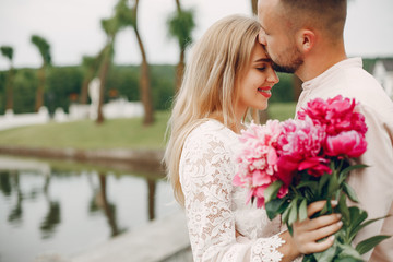 Wall Mural - Cute couple in a park. Lady in a white dress. Guy in a white shirt.