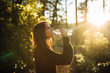 Young woman drinking water from bottle in nature.Bottled water.Hydration.Water intake for healthy body and skin.Natural mineral water spring.Fresh mineral iso-tonic drink.