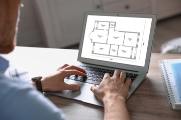 Canvas Print - Architect making project of house on laptop at table indoors, closeup