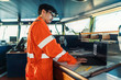 © Igor Kardasov - Filipino deck Officer on bridge of vessel or ship wearing coverall during navigaton watch at sea . He is using laptop, electronic paperwork at sea, concept of reporting