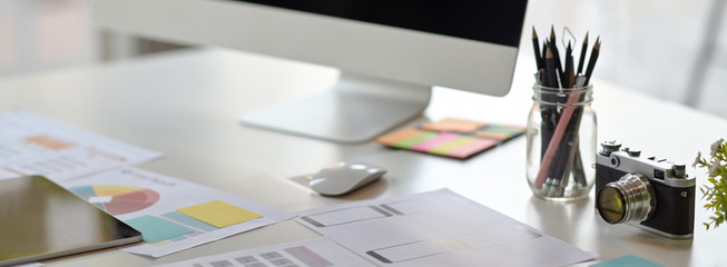 cropped shot of ui developer workspace with computer, stationery and paperwork