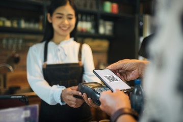 Customer paying with qr code on smartphone screen NFC payment technology at coffee shop.