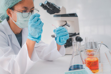 Wall Mural -  Female researchers are experimenting with pipette dropping a sample into a test tube in an experiment research in laboratory.