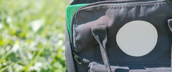 banner, black school bag on a grass. back to school concept. backpack with book. education concept. learning at school or univercity.