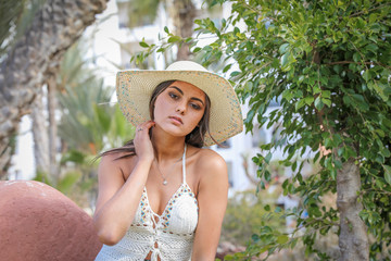 Summer time. Beautiful young brunette in a hat on a nature summer day.