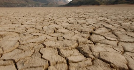 Wall Mural - Dynamic shot of cracked soil ground of dried lake or river in mountains. Land destroyed by erosion and global warming - ecological issues concept 4k footage