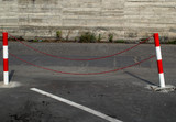 Fototapeta  - Tilted pole red and white Stand chain barrier, metal fence barricade in car park with concrete background